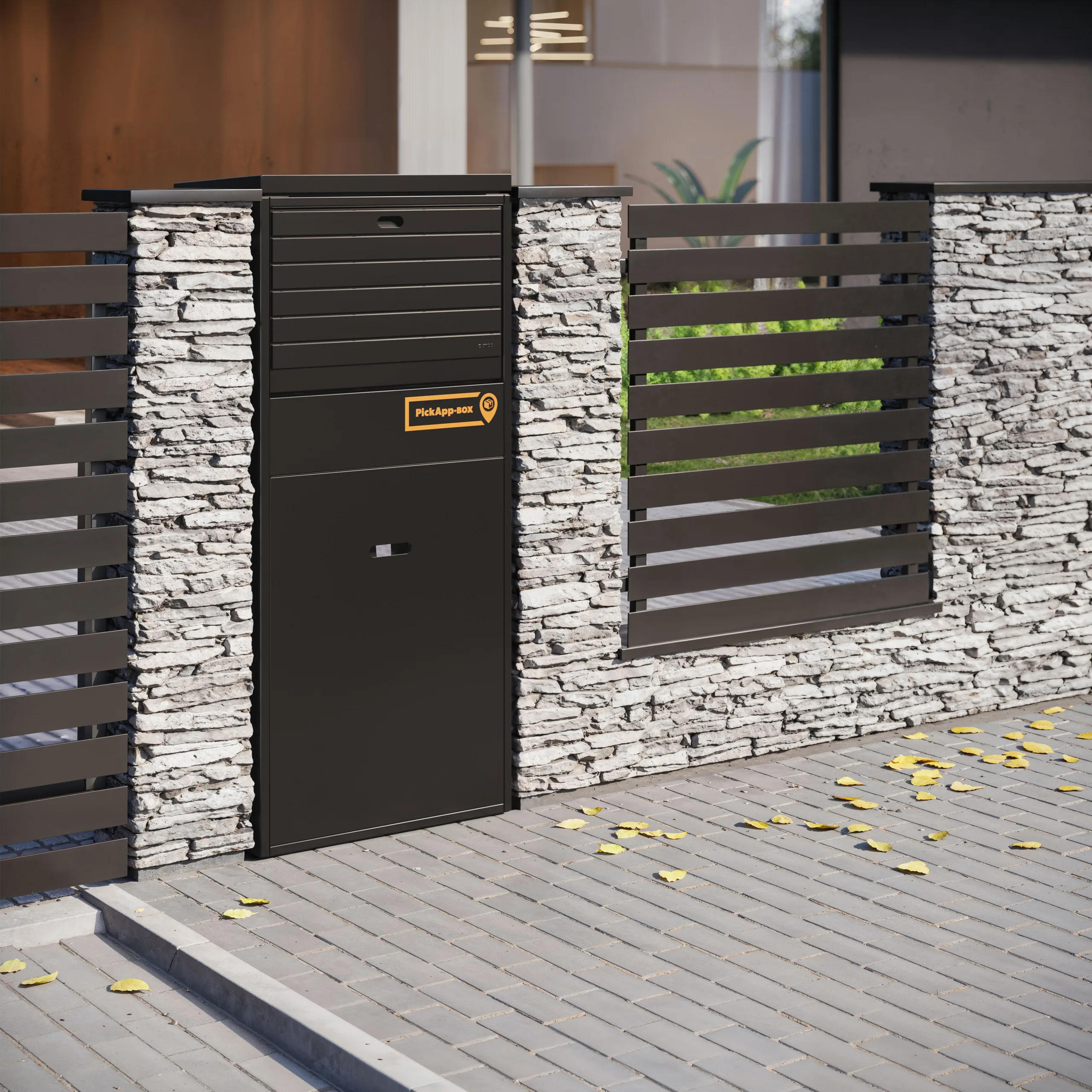 Tall matte-black parcel locker with an orange "PickApp-BOX" label built into a white stacked-stone fence beside horizontal dark metal slats, set above a gray paved walkway strewn with yellow leaves. 3D CGI Visualization Rendering