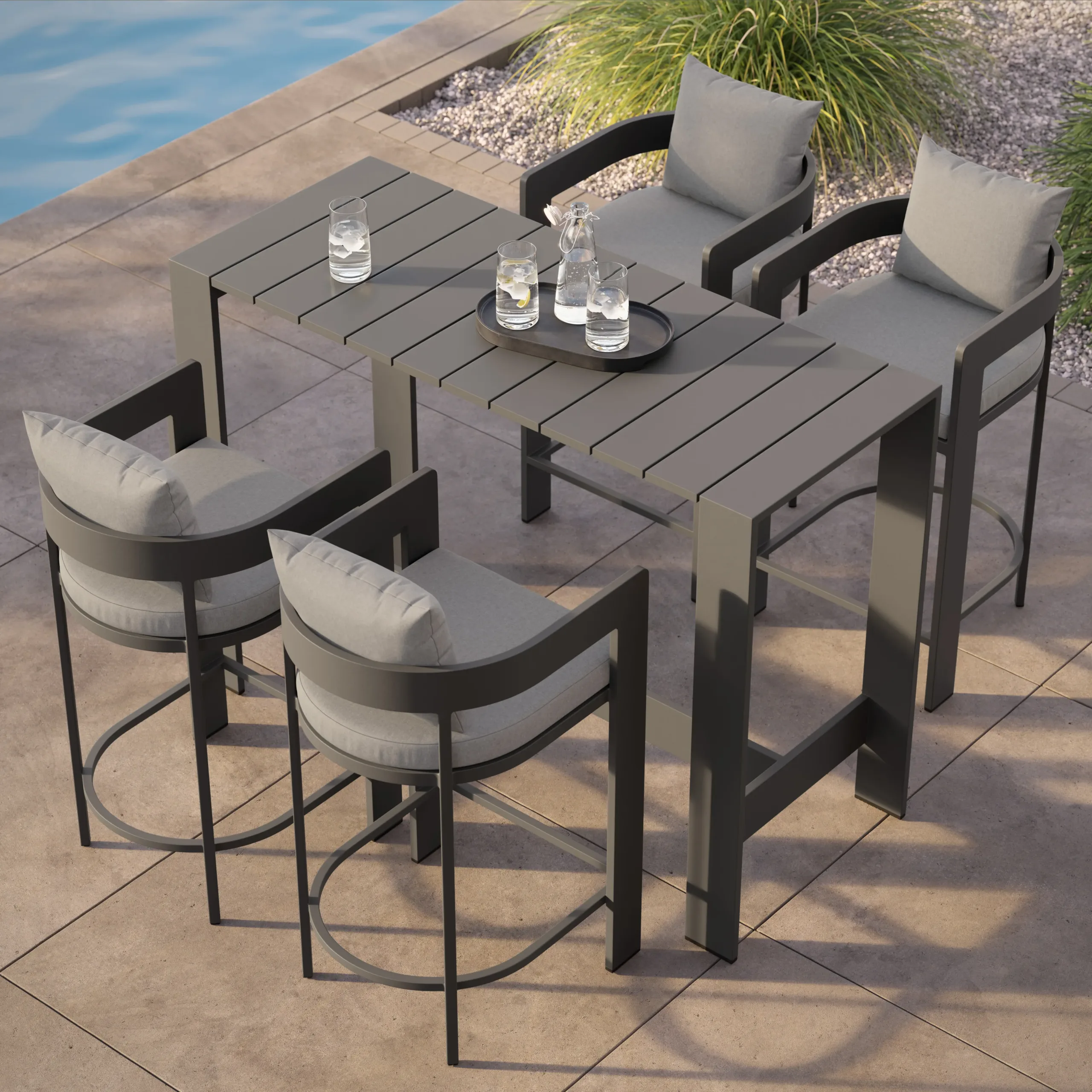 Gray slatted high table with four cushioned bar chairs and a tray of water glasses by a pool.