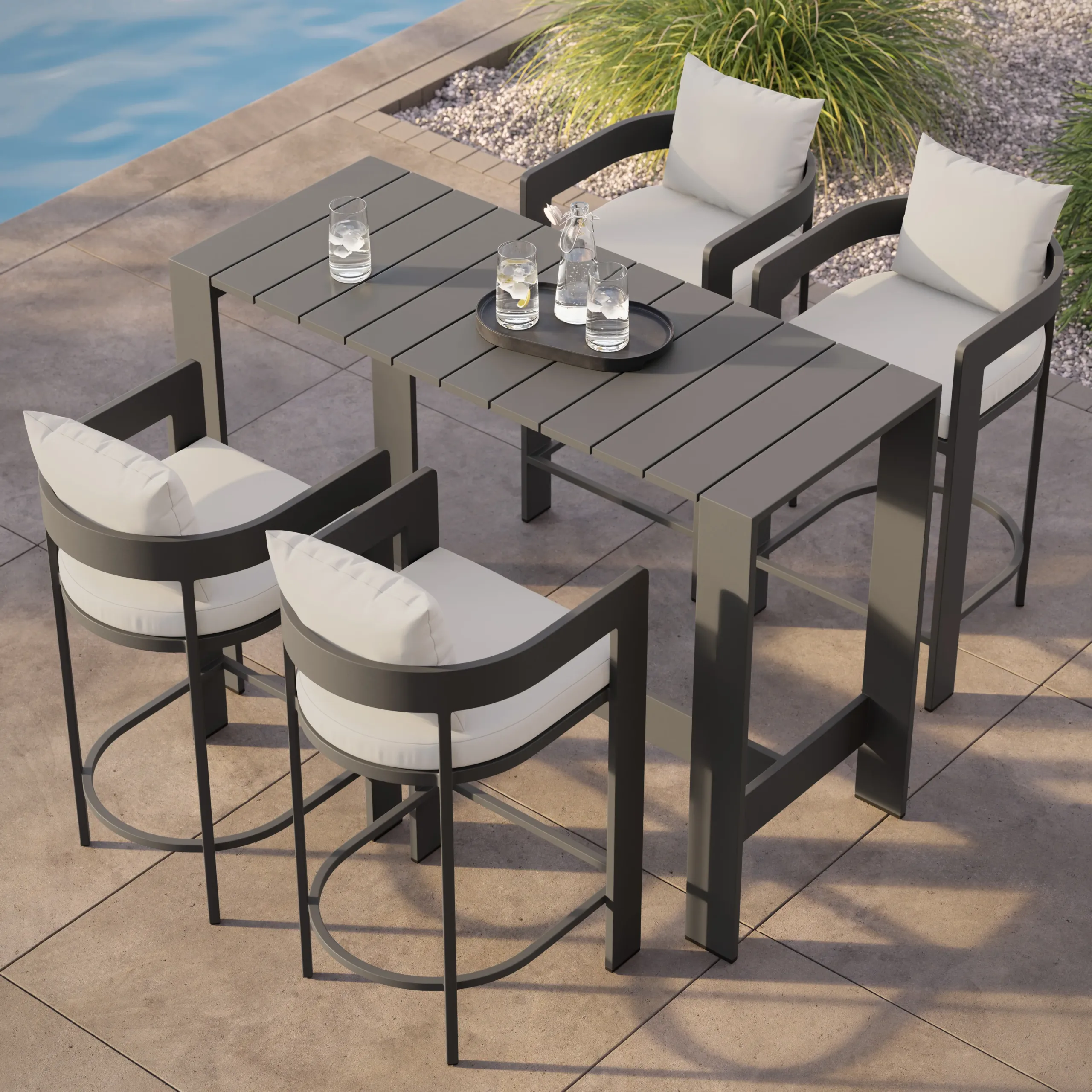 Gray slatted outdoor bar table with four cushioned metal bar stools and a tray of water glasses beside a pool