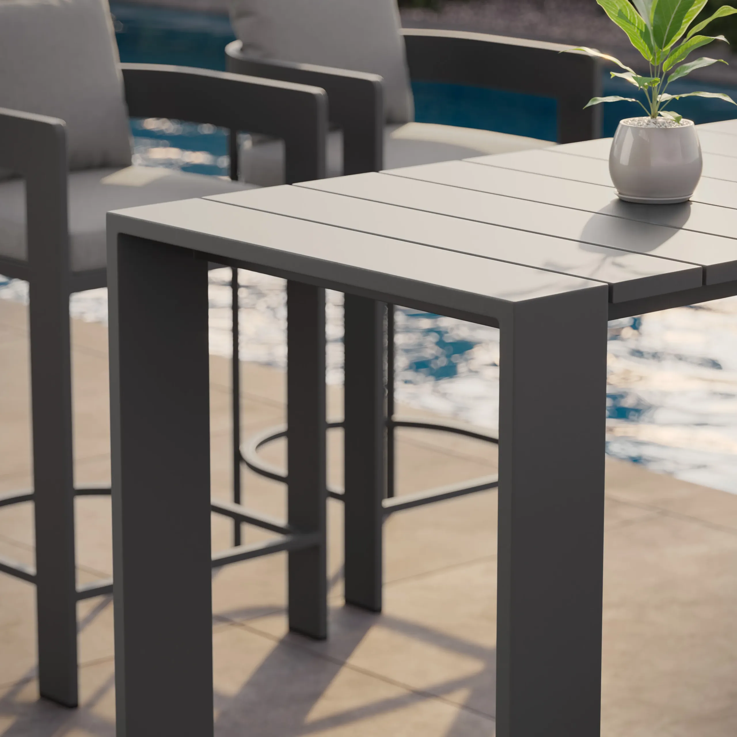 Slim gray slatted outdoor bar table with matching high stools and a small potted plant beside a pool.